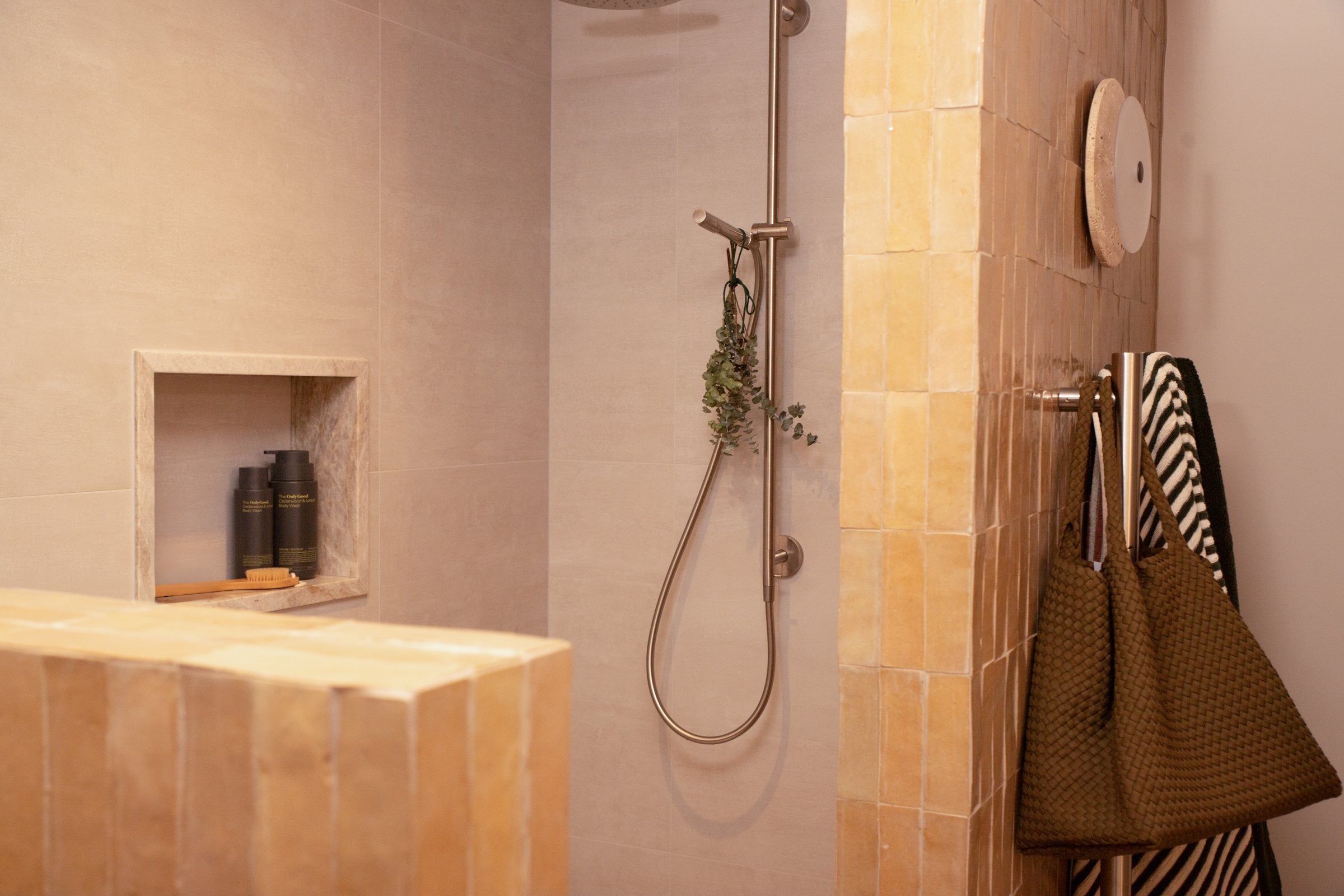 A stone shower with the Cedarwood and Juniper Hand Wash in the wall niche.