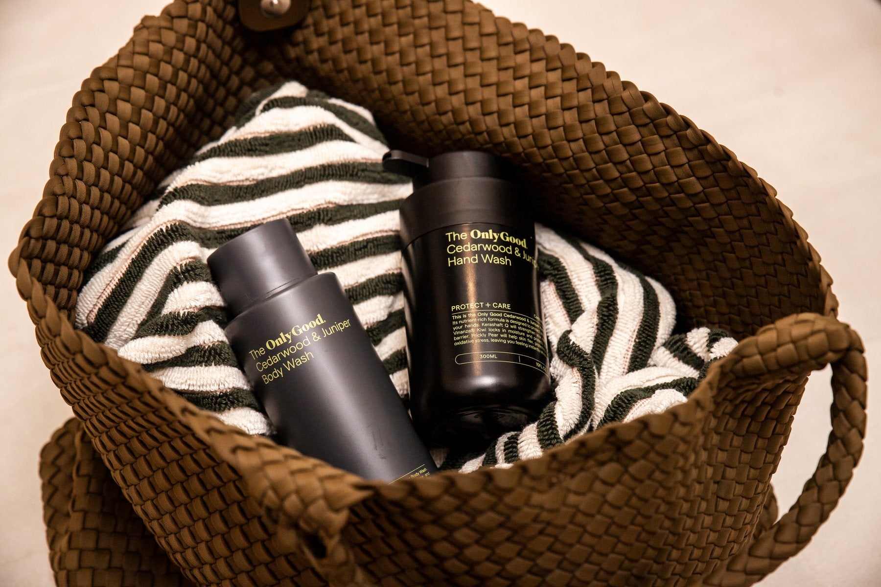 Only Good® Cedarwood & Juniper hand and body wash in a woven basket with a striped towel.