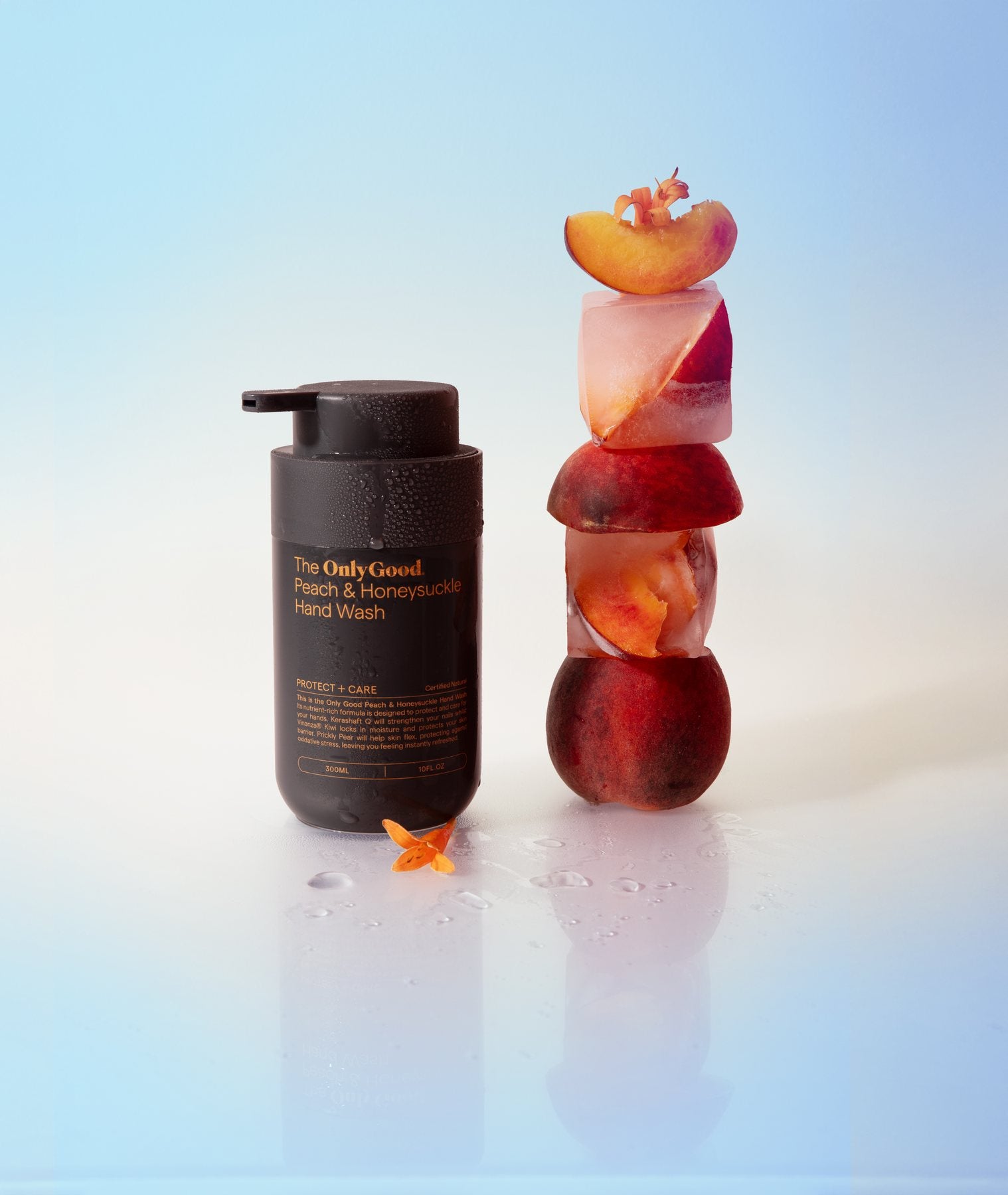 Only Good® Peach & Honeysuckle Hand Wash beside a stack of peaches set in ice.