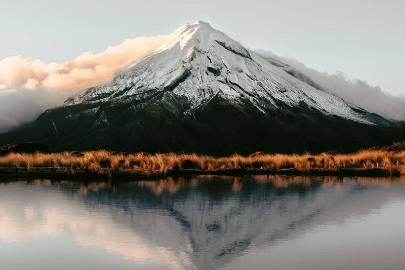 Mount Taranaki reflected in a still lake at dusk, New Zealand.