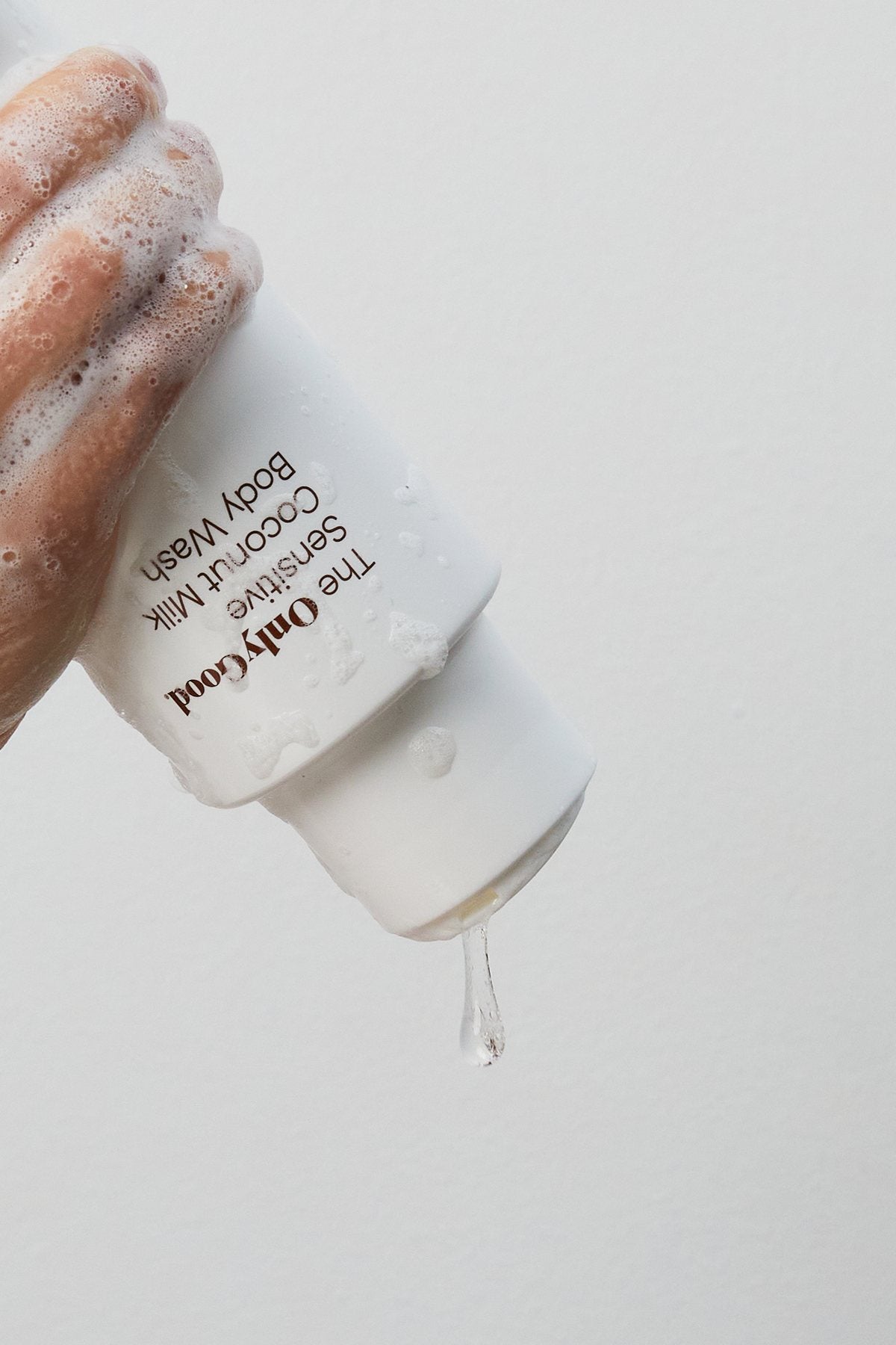 A thread of clear wash poured from the Coconut Milk Body Wash.