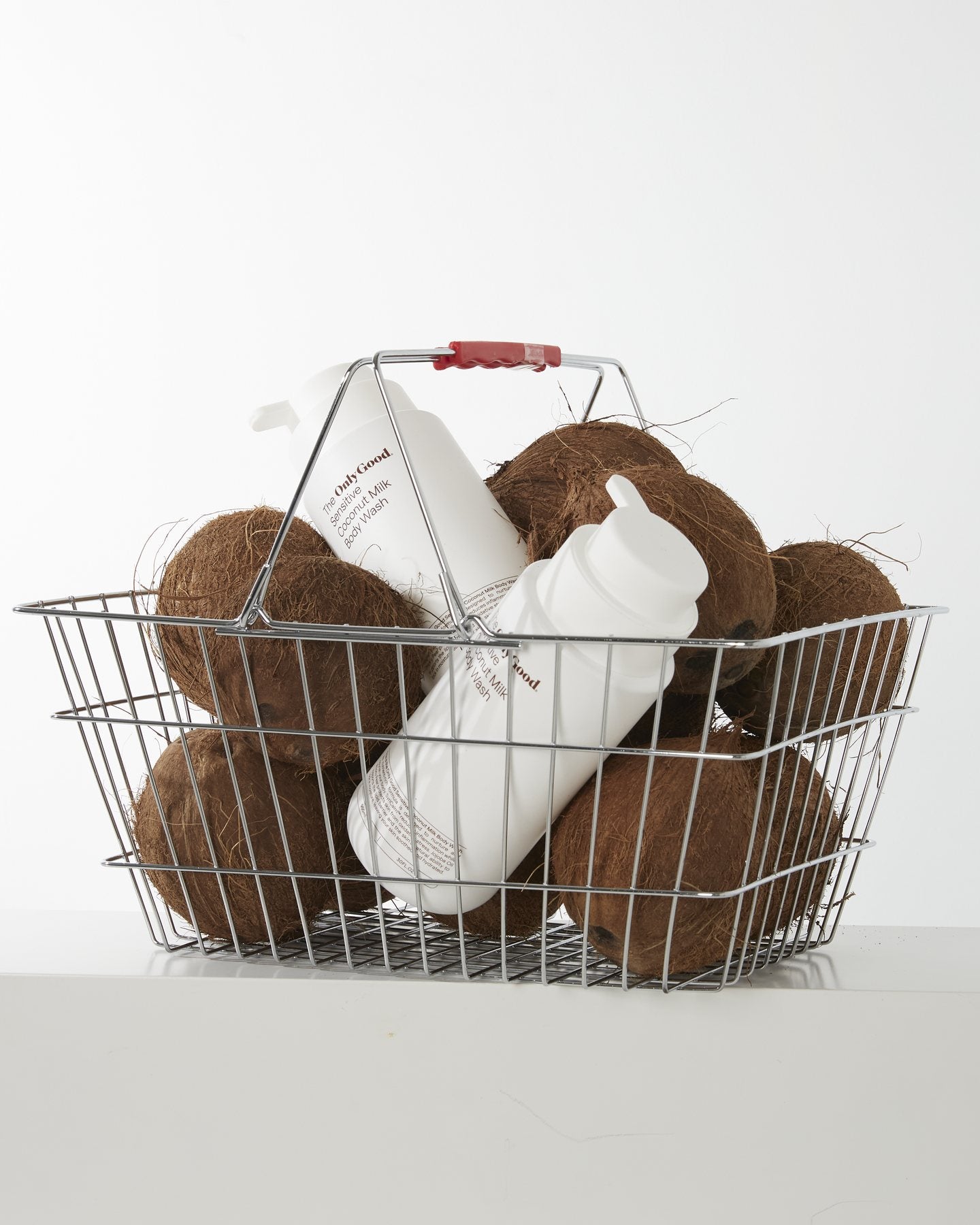 Only Good&reg; Coconut Milk in a wire basket of whole coconuts.